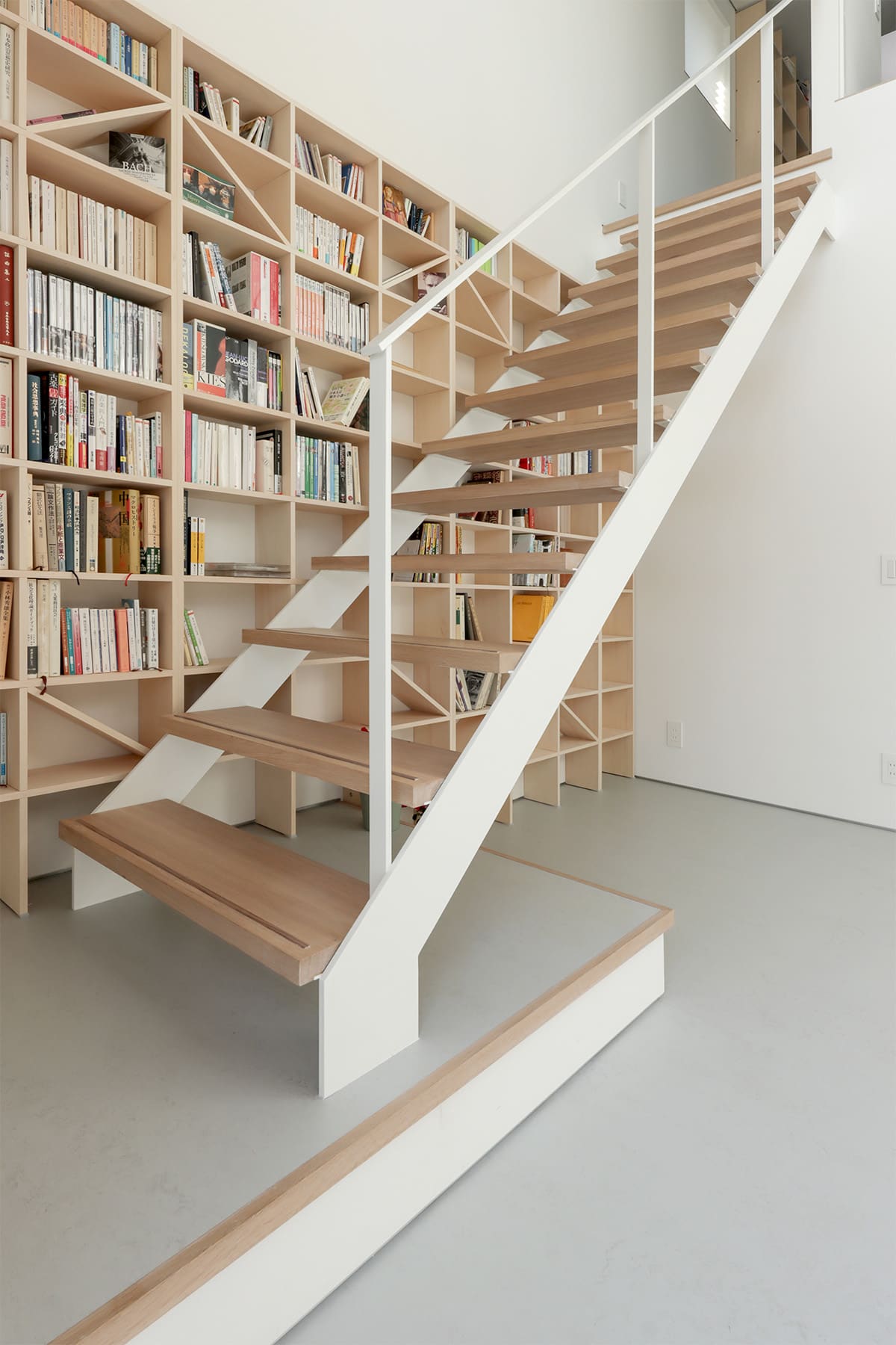 吹き抜けを介して1階および2階に設置された本棚 - Shelf 壁一面のA5本棚 奥行180mm/壁一面の本棚 奥行250mm - マルゲリータお客様事例