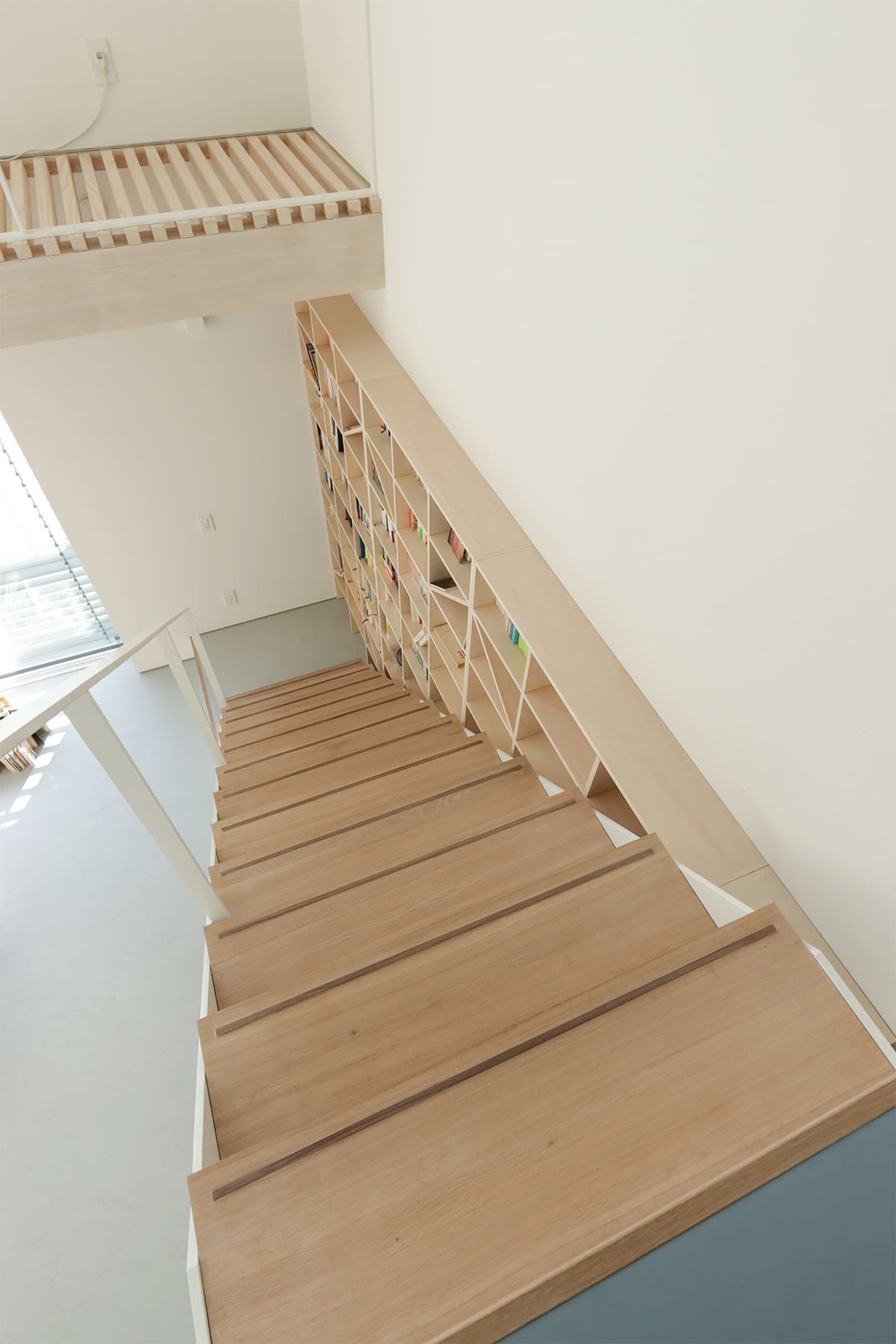 吹き抜けを介して1階および2階に設置された本棚 - Shelf 壁一面のA5本棚 奥行180mm/壁一面の本棚 奥行250mm - マルゲリータお客様事例